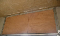 panneaux de bois pour stabiliser les vibrations de la porte automatique du parking souterrain de la copro